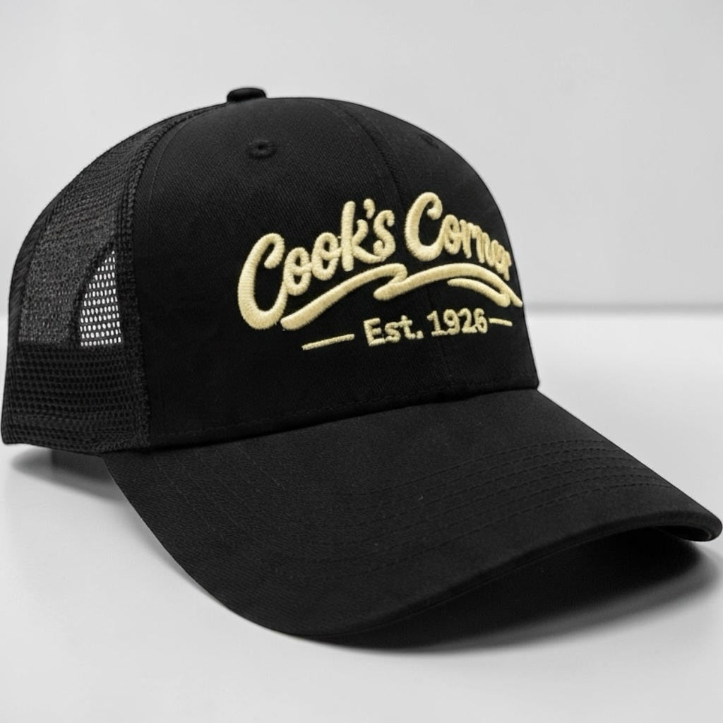 Cook's Corner black trucker hat with mesh back and embroidered logo on the structured front panel.